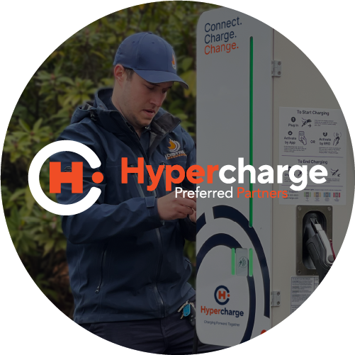 A man in a blue uniform operates an electric vehicle charging station outdoors. The Hypercharge Preferred Partners logo is displayed over the image.